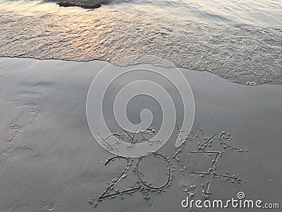 â€œbye bye 2017â€ on the beach with sea waving when sunset Stock Photo